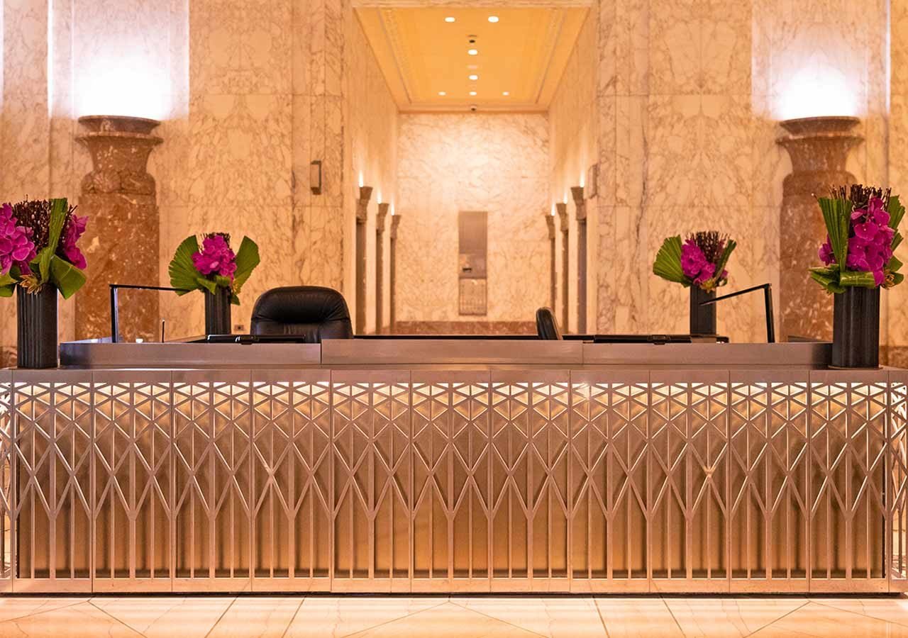 Floral arraingements on a building lobby desk, viewed from the front.