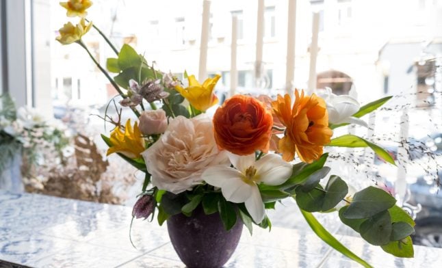 fresh floral arrangement with orange ranunculus yellow tulips and greenery for Long Island commercial decor