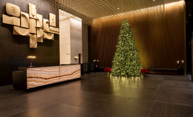 grand NYC commercial building lobby with decorated Christmas tree and ornate gold accent wall during holiday season