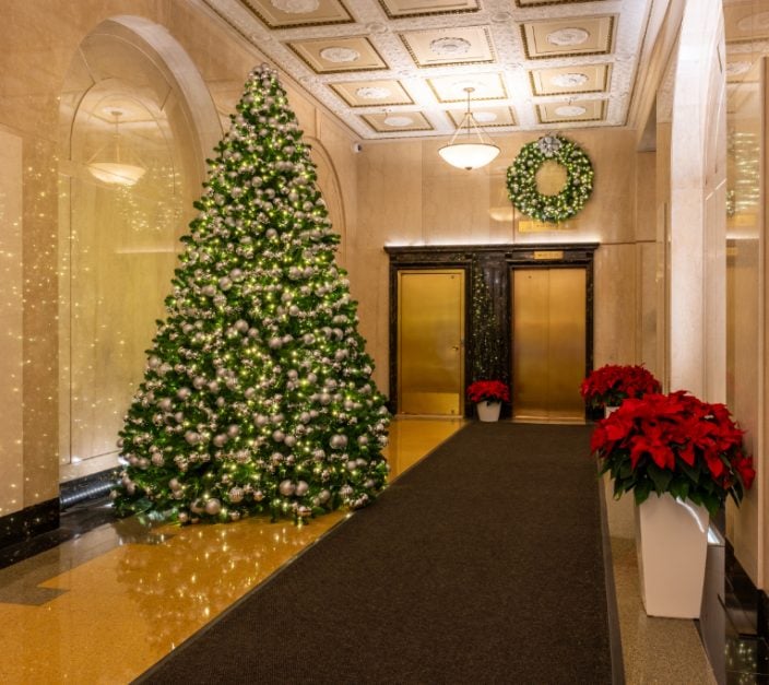 historic NYC commercial building lobby decorated for holidays with Christmas tree greenery wreaths and poinsettias