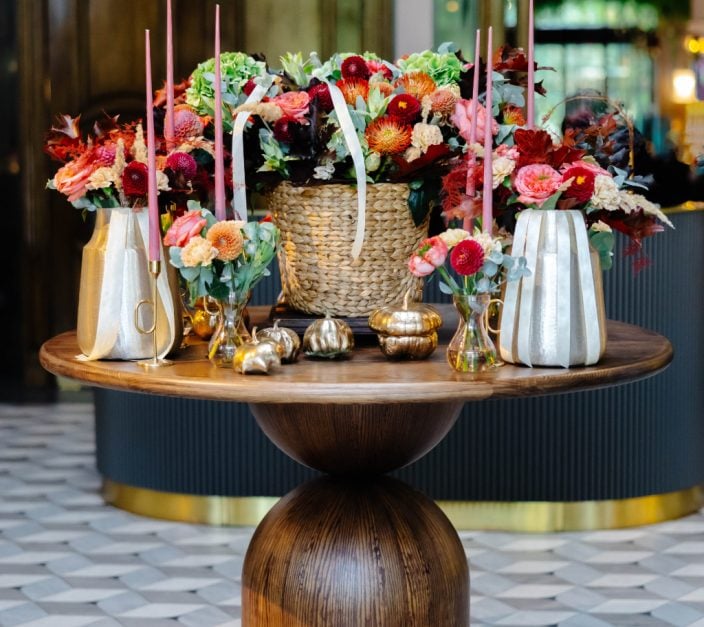 autumn floral arrangement with dahlias roses and taper candles on wooden table in elegant NYC hotel lobby