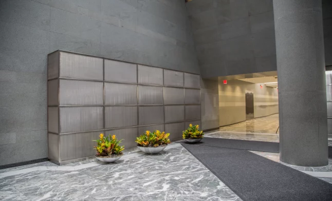 low bowl planters with tropical croton plants in a modern commercial building lobby with marble floors